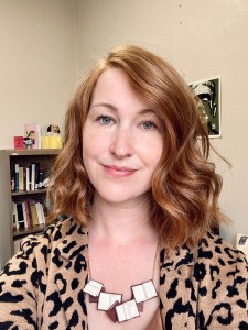 A close-up of a white woman with red hair and a leopard blazer